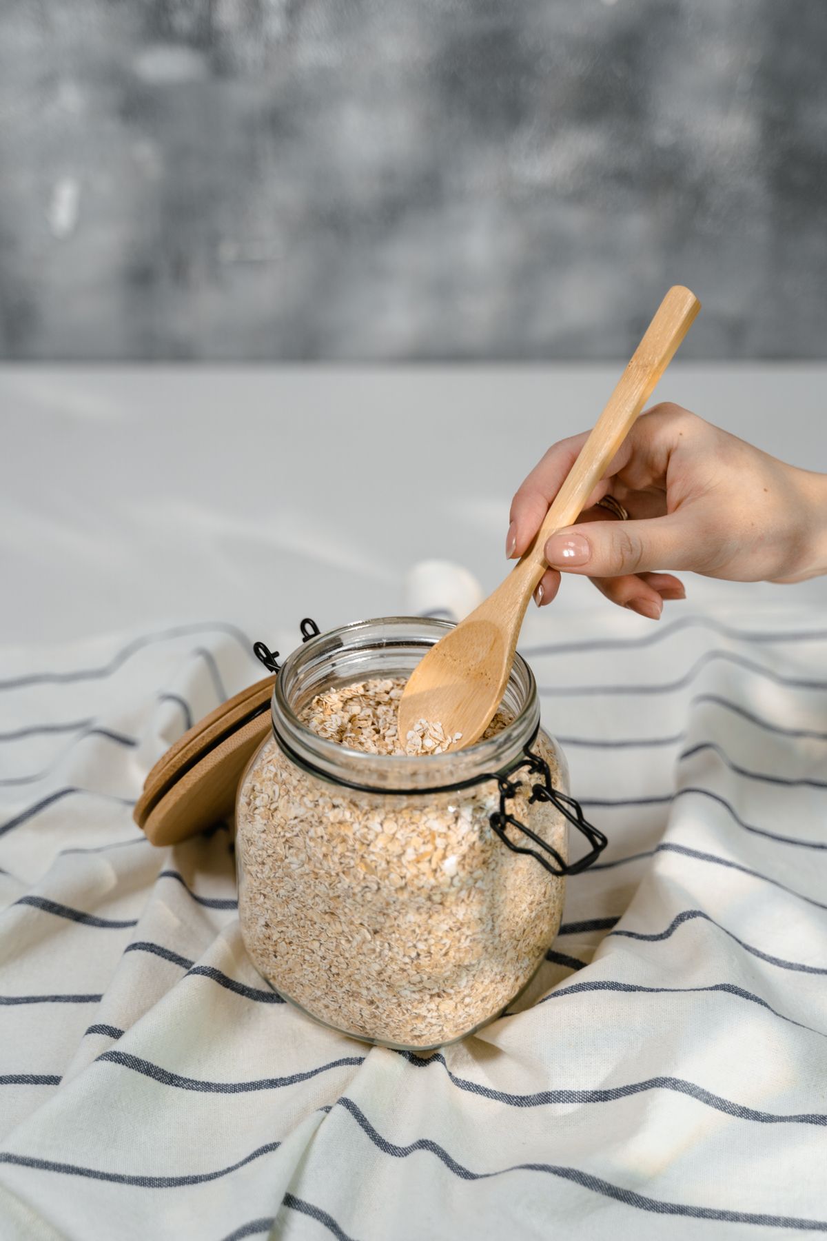 Rolled oats being scooped from a glass jar