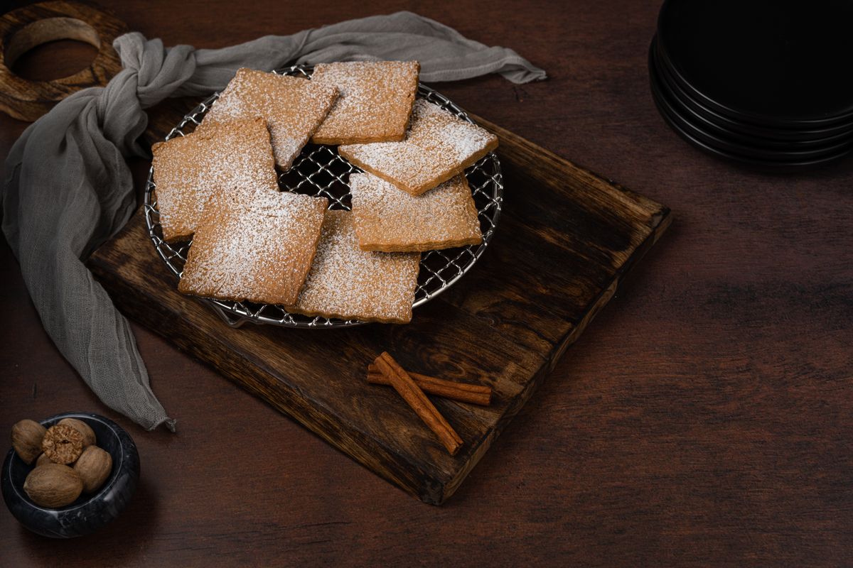 Biscuits dusted with sugar beside cinnamon sticks