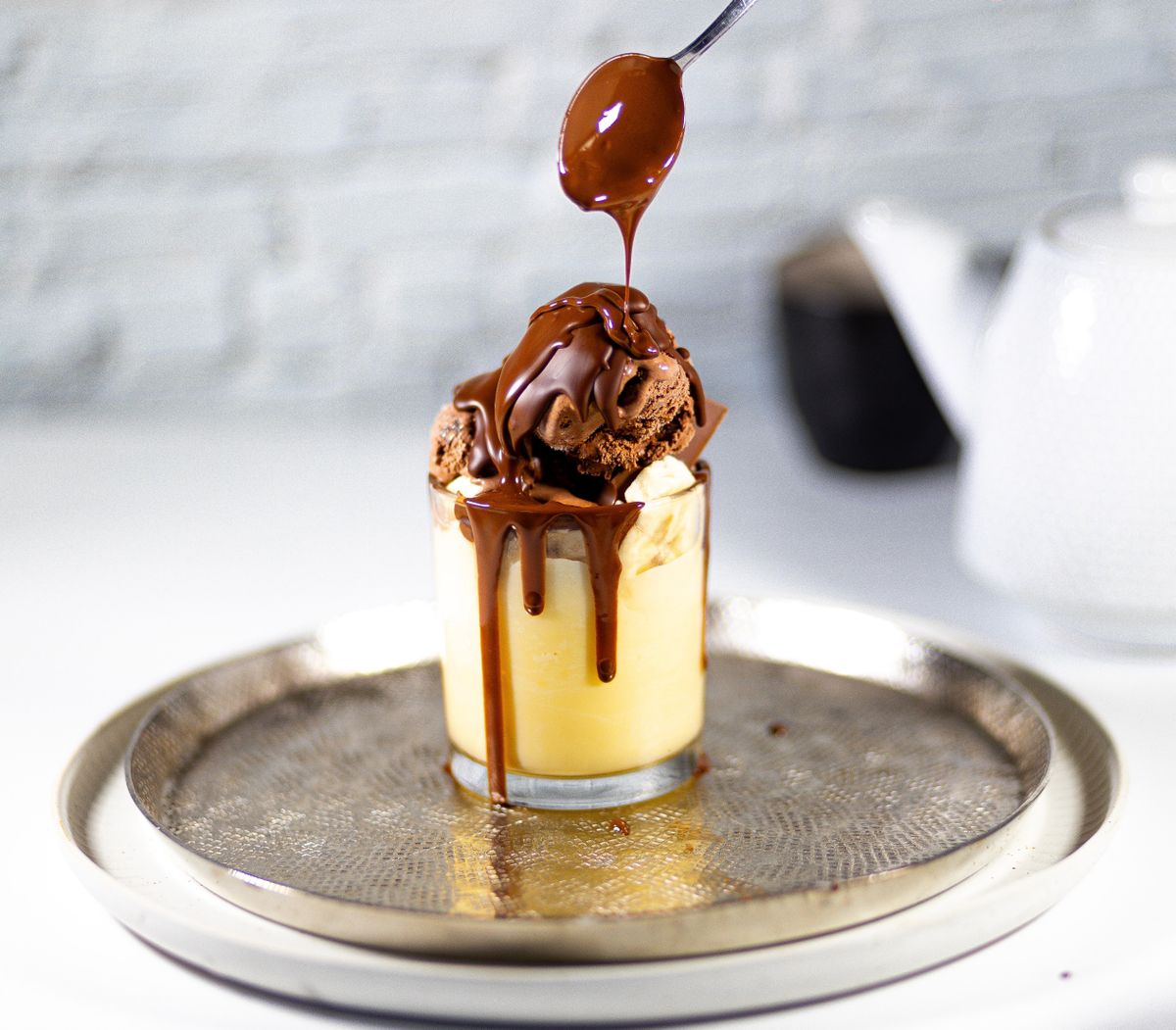 Chocolate sundae with chocolate sauce being drizzled over it