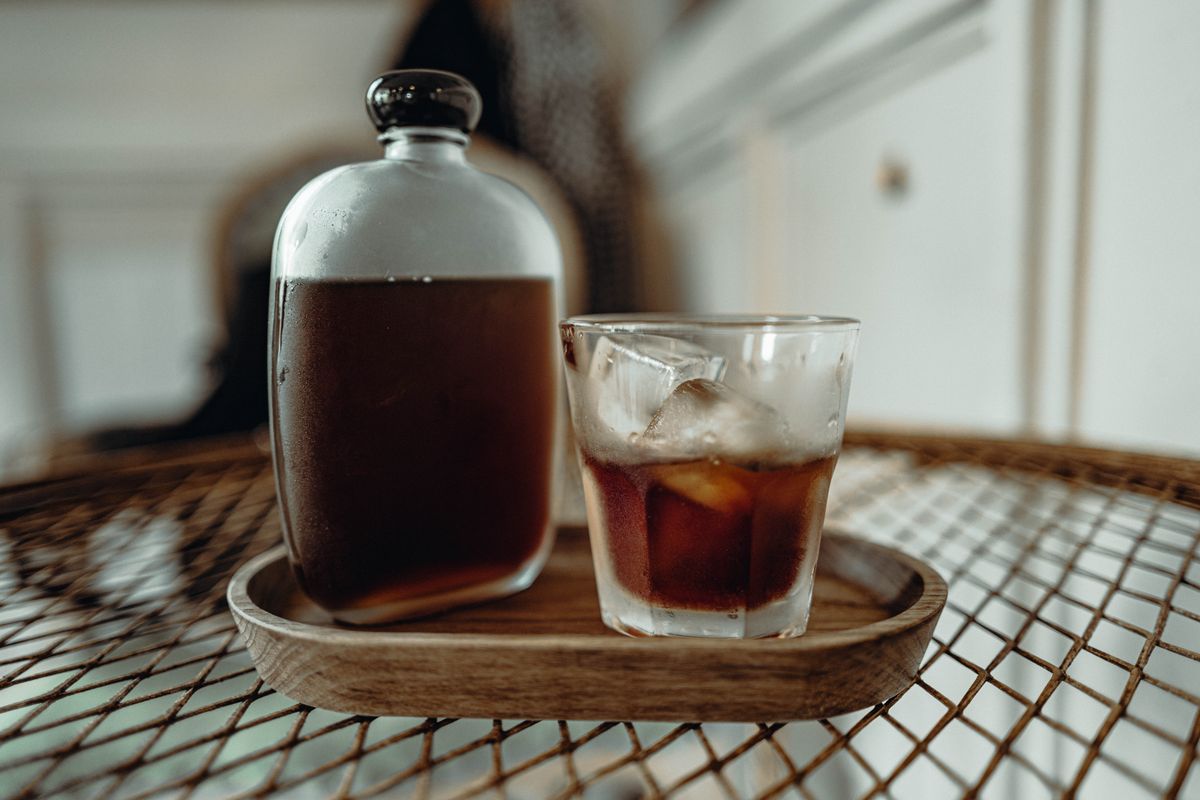 Cold brew coffee in a glass with ice on a wooden tray