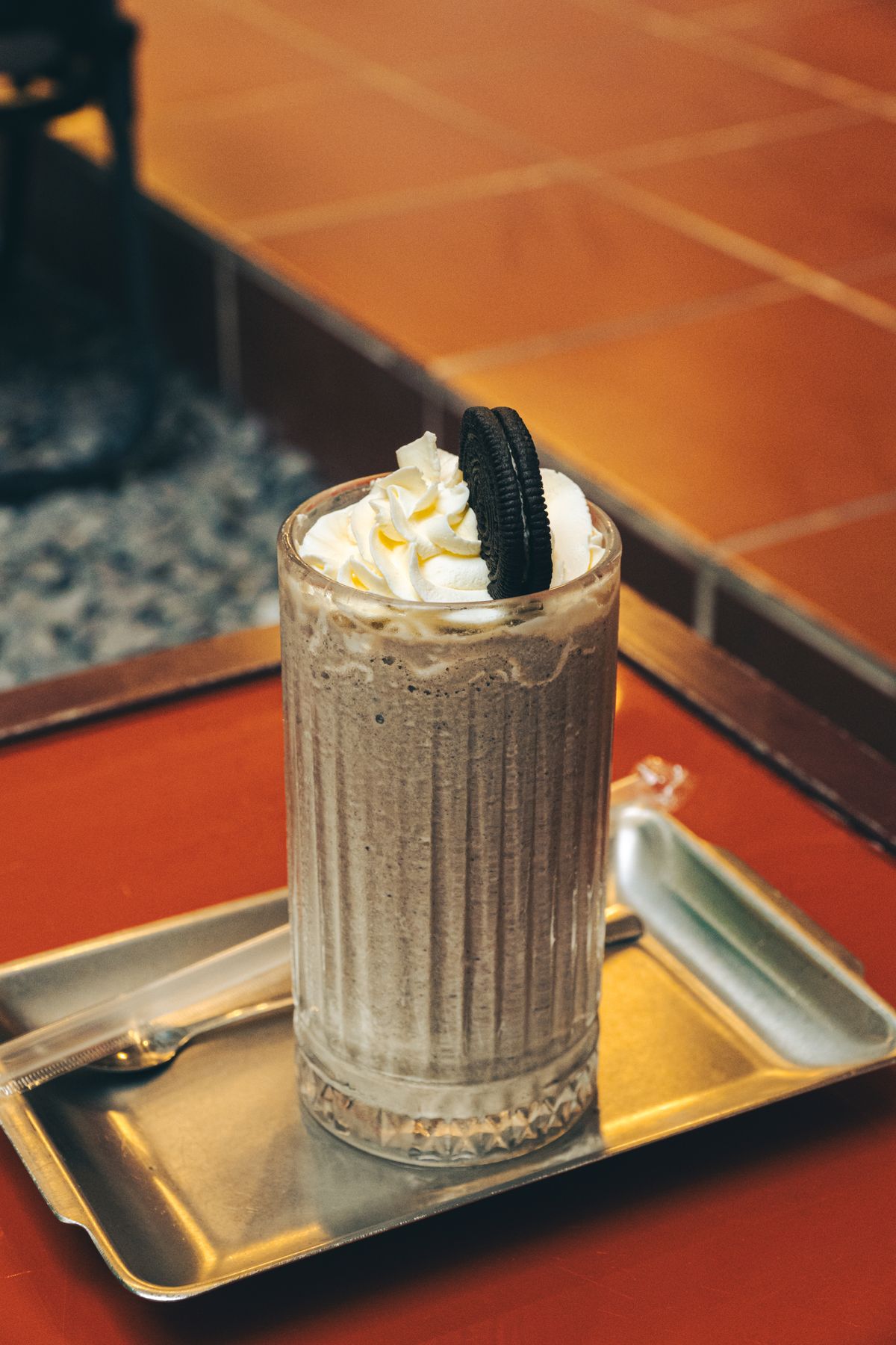 Cookies and cream milkshake topped with cream and a chocolate sandwich biscuit