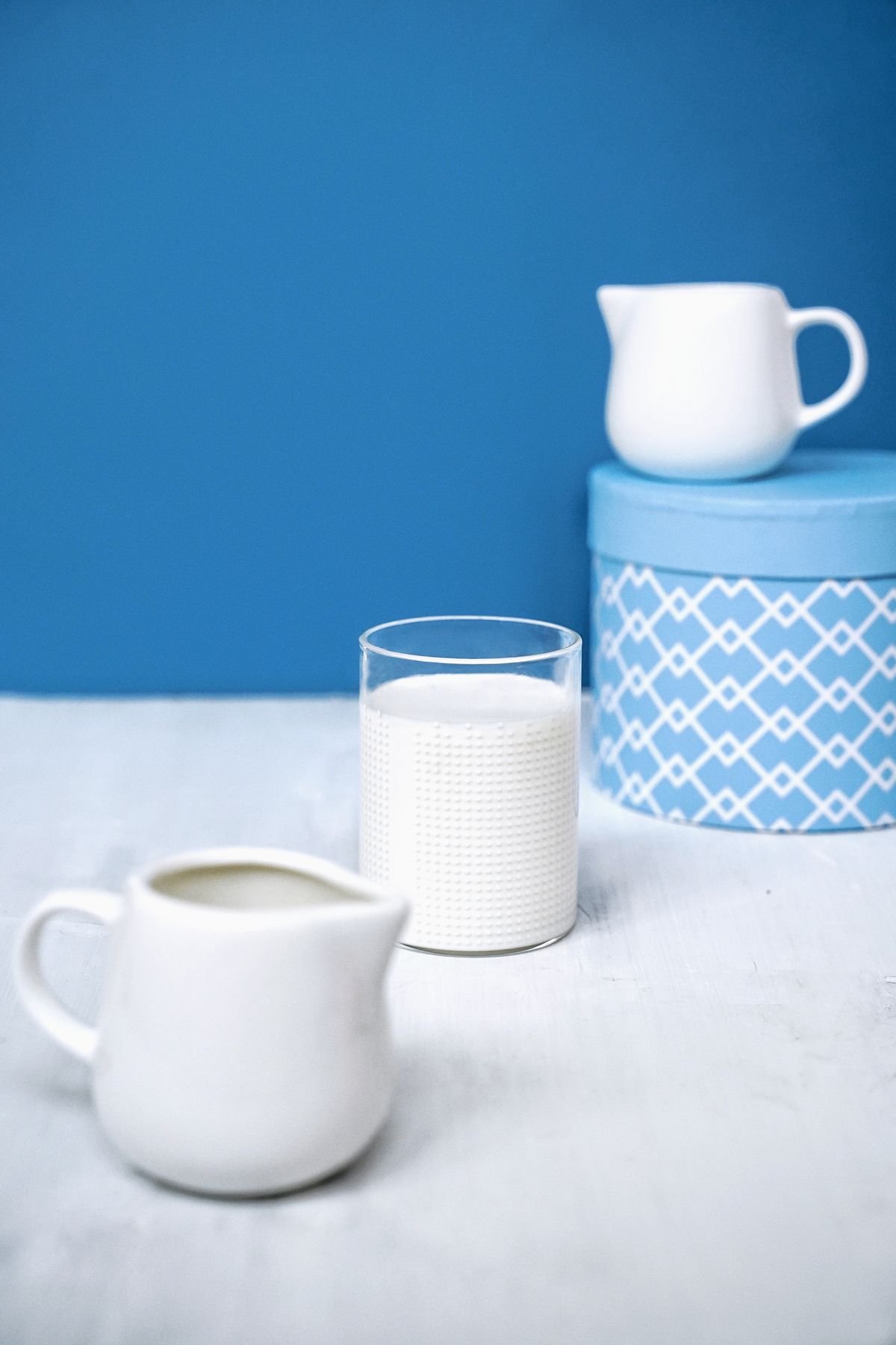 Milk jug and glass on a blue background