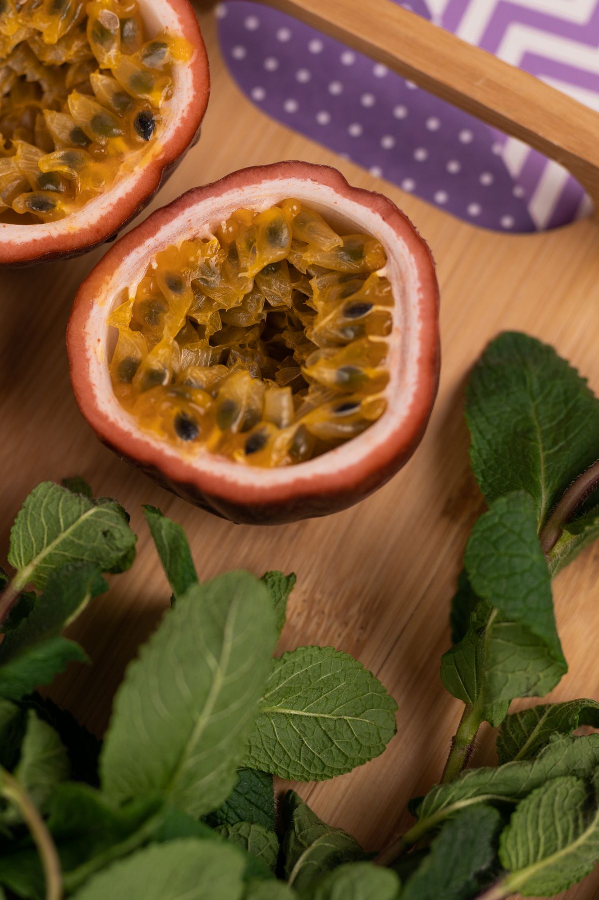 Halved passionfruit with mint on a chopping board