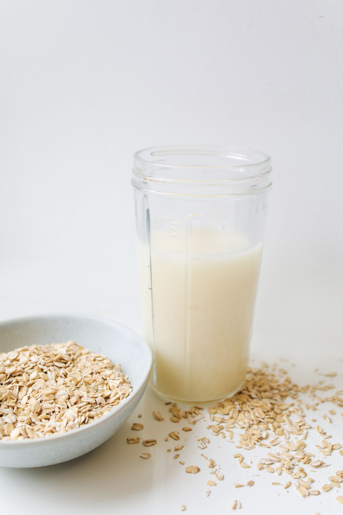 Oat milk beside a bowl of rolled oats