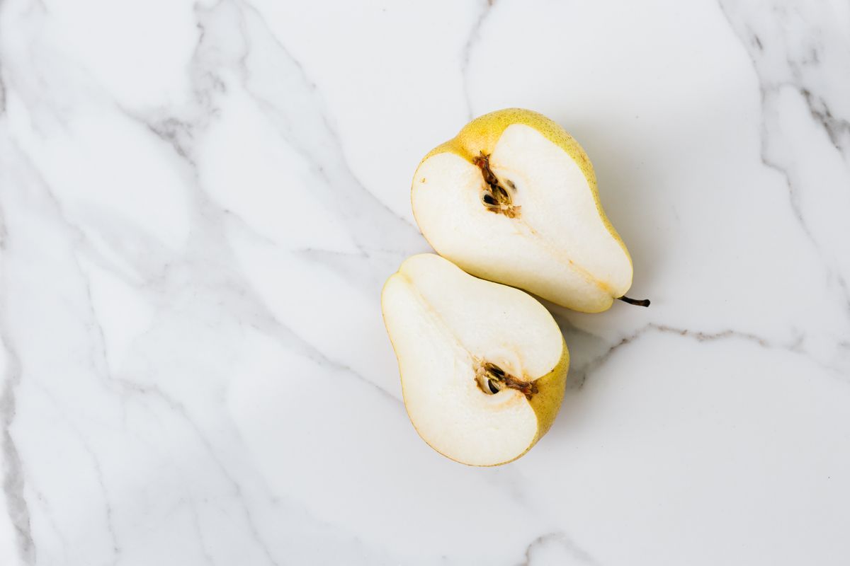 Fresh pear cut into slices on a marble surface
