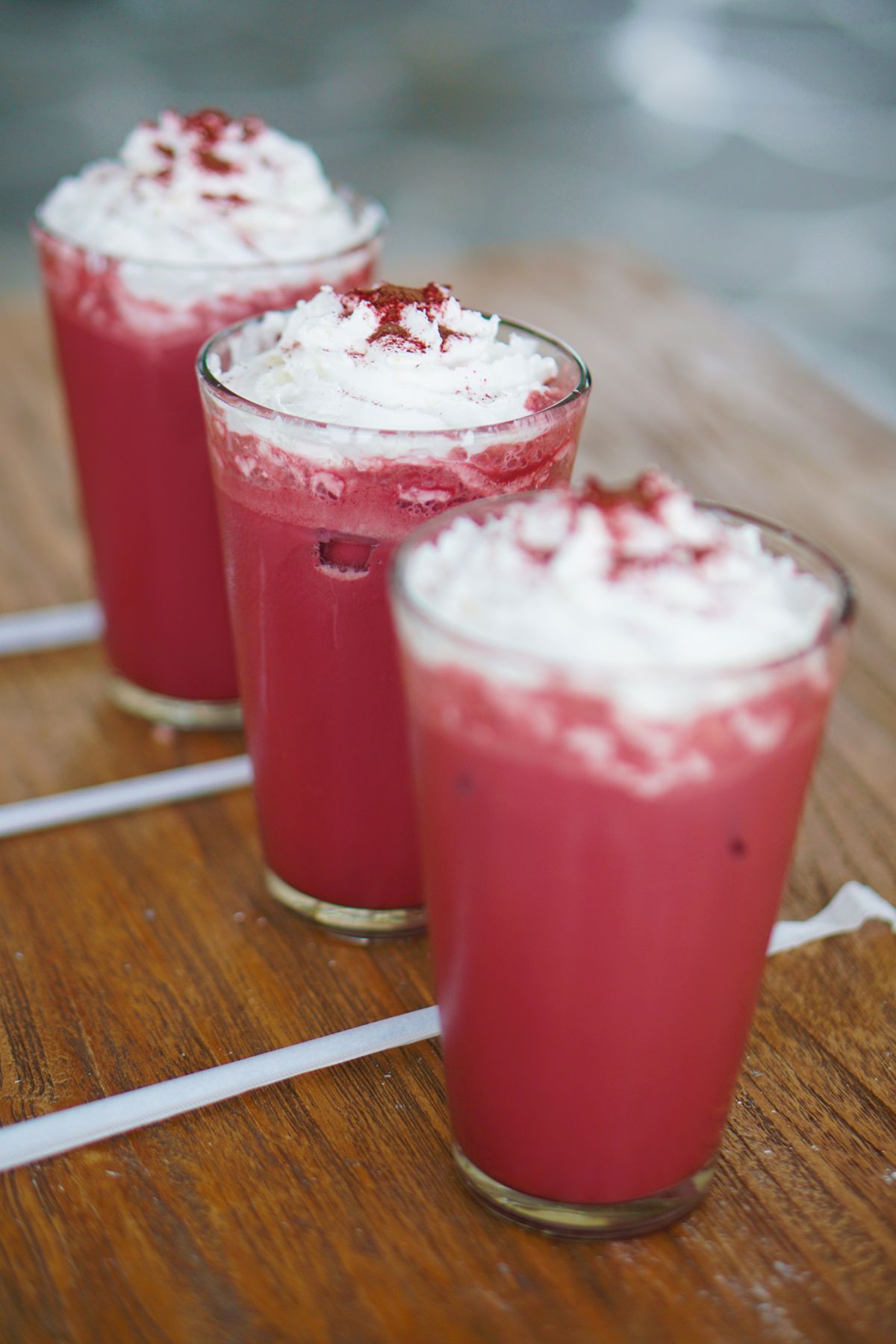 Three individual strawberry milkshakes in glass cups