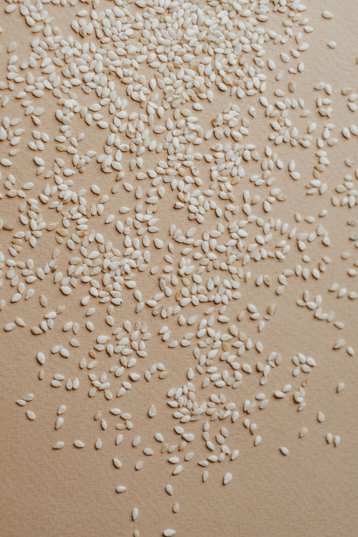 Raw sesame seeds scattered on a pale surface